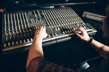 man's hands on the music board. close up sound engineering . close up cropped photo.