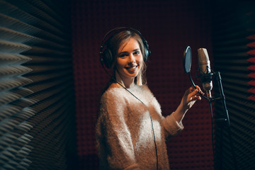 smiling beautiful girl looking at the camera while standing in the recording studio. close up photo