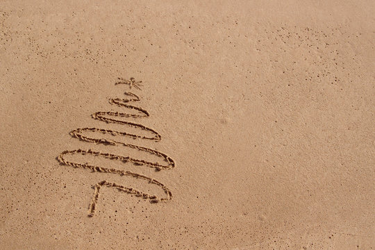 Christmas tree drawn in sand at the beach