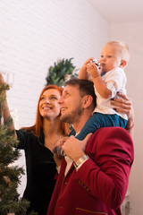 Fototapeta premium Young Happy Family Dressing Up The Christmas Tree
