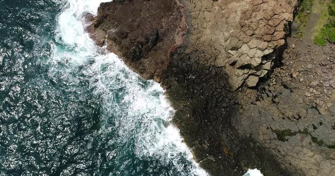 Water surface along basalt pinnacle rocks of Bombo quarry – lifting view towards headland and horizon over sea.
