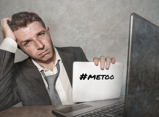 frustrated businessman desperate at office computer desk holding notepad with the hashtag me too...
