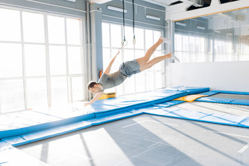 handsome guy is falling on the mats. full length side view photo. safely landing. fun