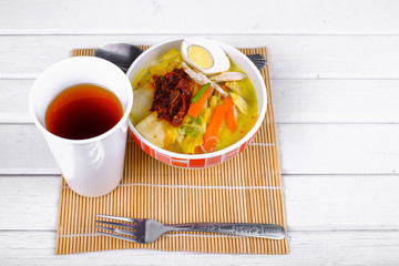 Lontong-Traditional Malaysian and   Indonesian food on wooden table with spoon.