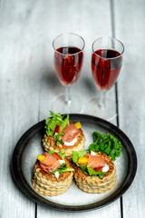French cuisine, crunchy patties with lettuce and smoked salmon on a bright, rustic background, next to a glass of red wine