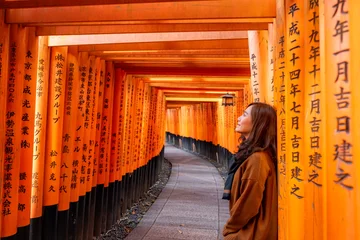 Rolgordijnen A beautiful asian woman with orange torii gates path in background © Farknot Architect