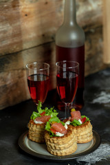 French cuisine, crunchy patties with lettuce and smoked salmon on a wooden, rustic background, next to a glass of red wine
