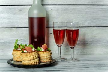 French cuisine, crunchy patties with lettuce and smoked salmon on a bright, rustic background, next to a glass of red wine