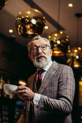Portrait of surprised senior businessman in drinking coffee near bar counter at elite gentlemen s club