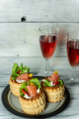 French cuisine, crunchy patties with lettuce and smoked salmon on a bright, rustic background, next to a glass of red wine