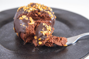 Rum ball decorated with chocolate and nuts eaten with a fork on a white background