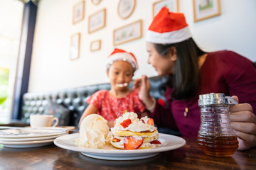 Family enjoy eating cake in Christmas Eve holiday celebration in cafe or restaurant