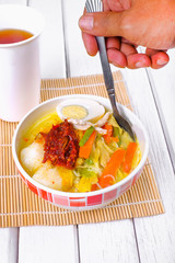 Lontong-Traditional Malaysian and   Indonesian food on wooden table with spoon.