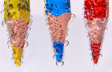 Close-up of three colored pencils in soda water with bubbles isolated on white.