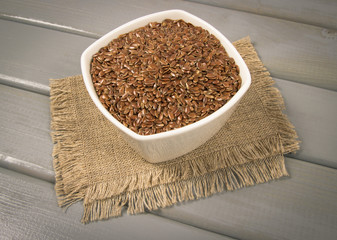 Linseed in a bowl on a wooden background.