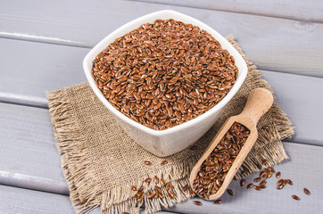 Linseed in a bowl on a wooden background.