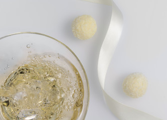 Champagne is poured into a glass and next to two candies