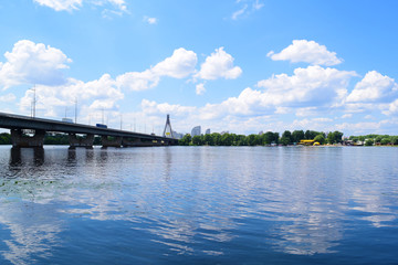 Fototapeta na wymiar View across the river on the long bridge in the city near nature.