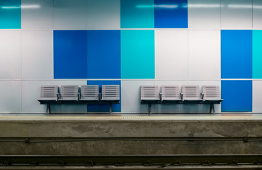 Metro station with empty plastic seats with blue boards in the back