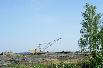Fototapeta premium A huge excavator carries rock from the unloaded train from the mine. The concept of mining and environmental problems.