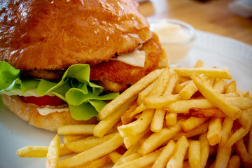 French fries with big burger on the white plate. The most popular fast-food item. Closeup food photo © AtjananC.