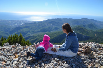 Naklejka na ściany i meble Mom and her little girl kid looking from mountains down to the sea