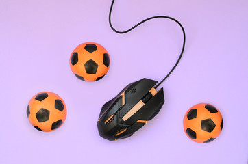 Optical gaming mouse lies next to several orange footballs. The concept of sports betting and...