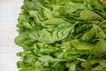 Spinach leaves on a wooden white table.