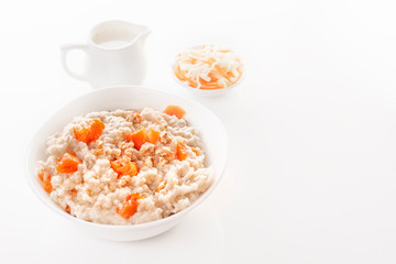 Fototapeta na wymiar Oatmeal with pumpkin and nuts in a plate, vegetable salad and a jug with milk on a white background. Close-up. Copy space