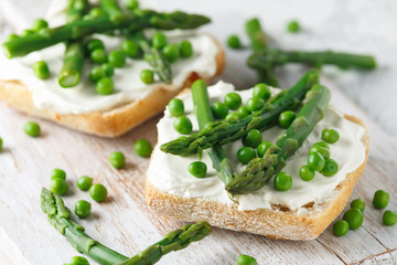 Appetizer bruschetta, toast with Asparagus, Peas and creamy soft cheese on white board. healthy food.