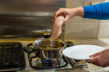 Putting chicken breast into simmering water to poach