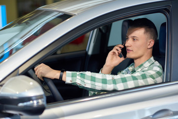 Handsome blonde man with handwatch sitting in grey car. 