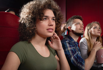 View from side of excited girl watching intriguing movie.