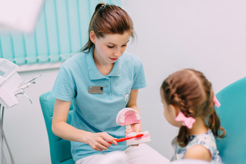 pediatric dentist teaches little girl to brush teeth