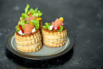 French cuisine, crunchy patties with lettuce and smoked salmon on rustic background