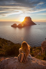 Woman back to the front watching a beautiful sunset at the beach. The beach is called Es Vedra