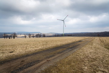 White wind turbine power station, foggy day, copy space on cloudy sky, sustainable renewable electricity concept