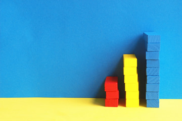 towers of red, yellow and blue toy blocks in front of blue wall