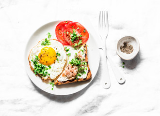 Breakfast served - fried egg, smoked mackerel cream cheese toast, tomatoes on a light background, top view