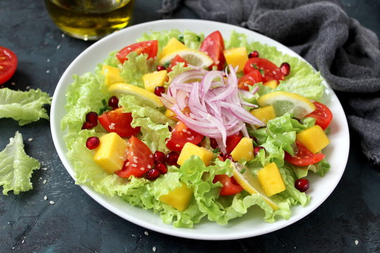 Fresh salad with lettuce, mango, tomato, onion, sesame and pomegranate. Diet food. Top view. Vegetarian and vegan food.