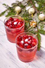 Glasses with cranberry juice on white wooden background with pine branch in the background. Christmas tree