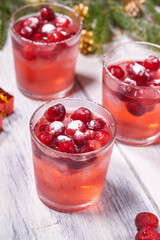 Glasses with cranberry juice on white wooden background with pine branch in the background. Christmas tree
