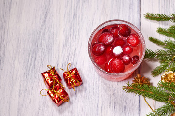 Glasses with cranberry juice on white wooden background with pine branch in the background. Christmas tre. Copy space