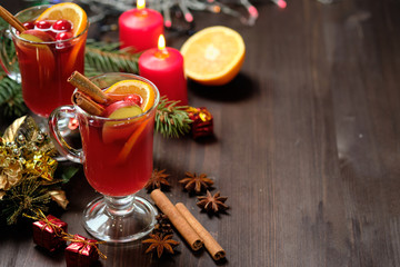Mulled wine on a wooden background with candles, pine branches and Christmas lights. Selective focus.  Copy space
