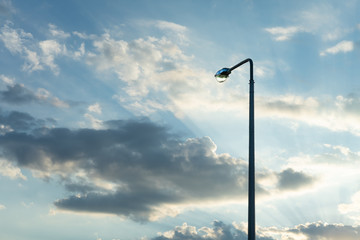 Lamppost on the background of the evening sky with the rays of the setting sun.