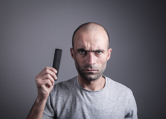 Caucasian bald man holding comb.