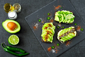 Rye avocado toast with chili and lime on a stone serving board. Healthy avocado toast. Top view. Flat lay.
