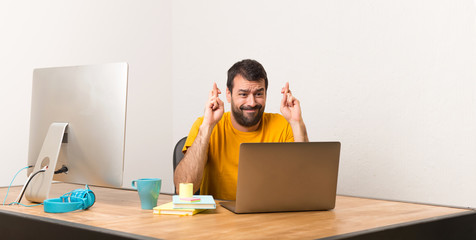 Man working with laptot in a office with fingers crossing and wishing the best