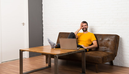 Man with his laptop in a room makes funny and crazy face emotion