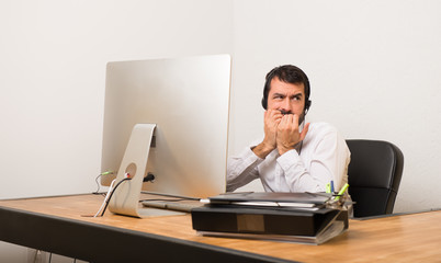 Telemarketer man in a office is a little bit nervous and scared putting hands to mouth